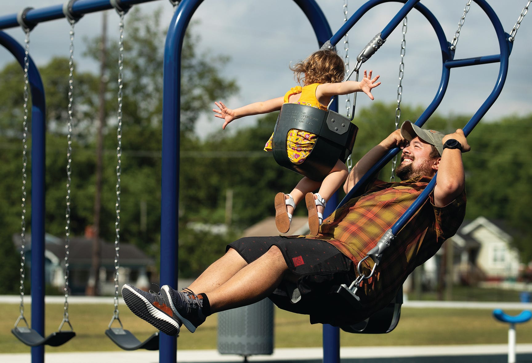 Adult and child using Expression Swing face-to-face at a playground