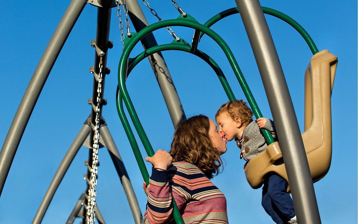Adult and toddler using Expression Swing Toddler face-to-face